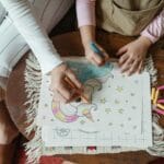 Jak wspólnie z rodzicami wspierać samodzielność przedszkolaka Mama i córka wspólnie kolorują rysunek jednorożca przy stoliku