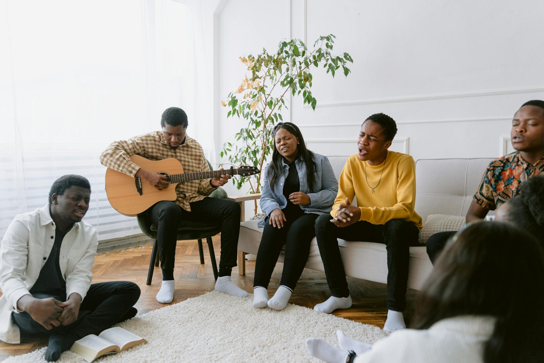 Przyjaciele śpiewają kolędy przy gitarze w przytulnym pokoju