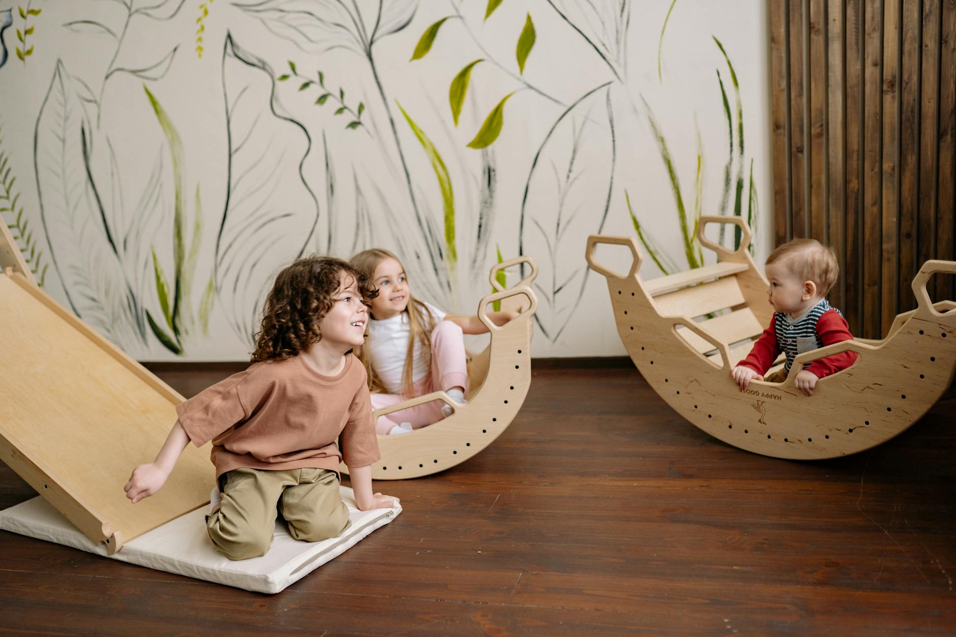 Bezpieczne zabawki dla 3–5 latka: jak wybierać bez stresu Dzieci bawiące się w domu na drewnianych zjeżdżalniach i bujakach