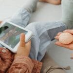 Dziecko ogląda bajkę na tablecie obok dorosłego z modelem mózgu