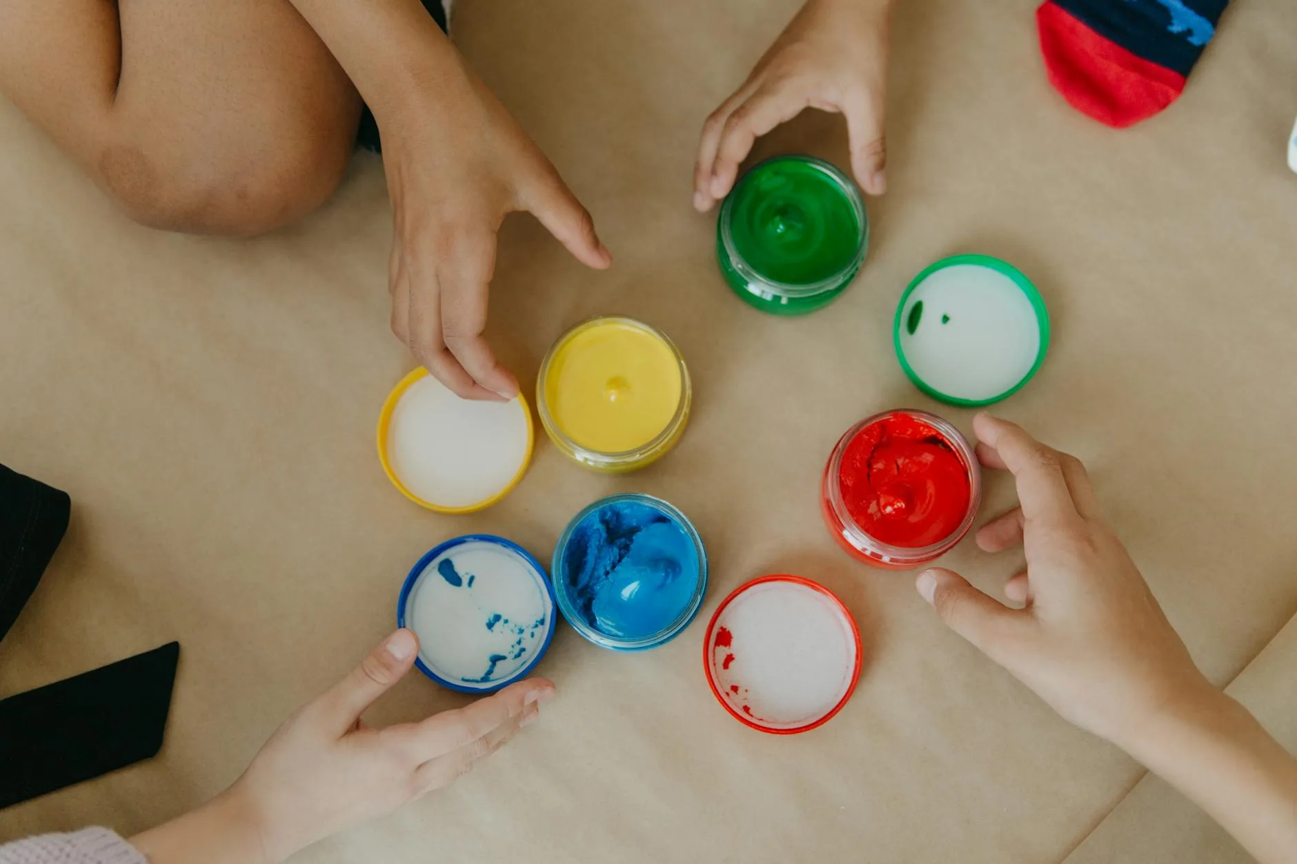 Dziecięce dłonie sięgają po kolorowe farby do twórczej zabawy