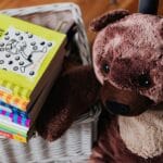 Stos kolorowych książek dziecięcych obok pluszowego misia w pokoju dziecka