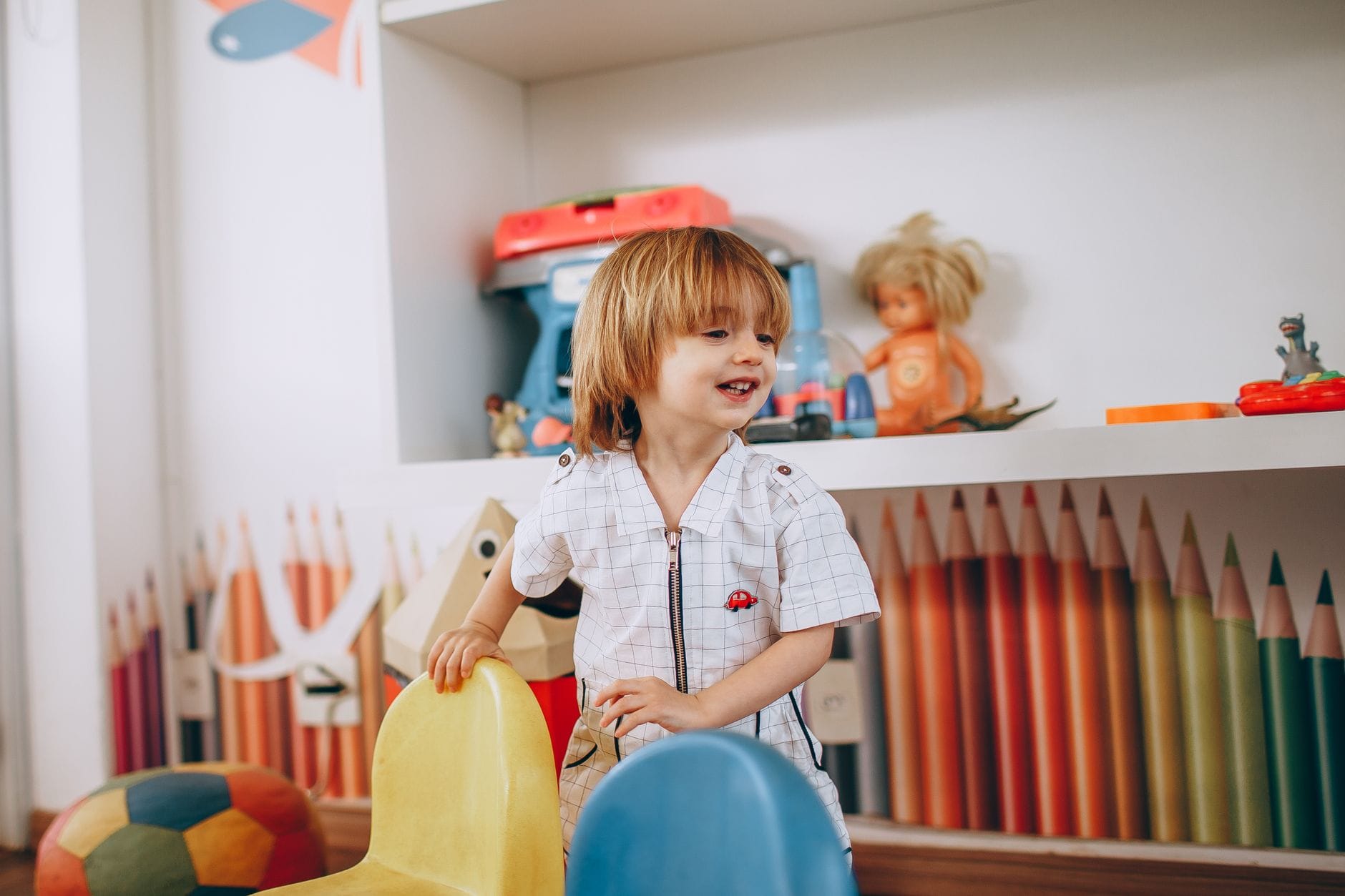 Uśmiechnięte dziecko bawi się w kolorowej sali przedszkolnej